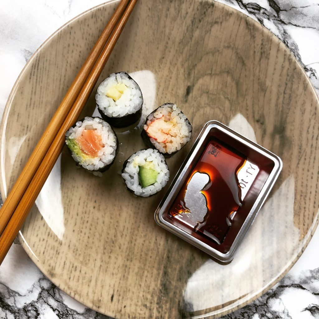 4 Rollen Sushi mit einer Schale Sojasauce und Essstäbchen